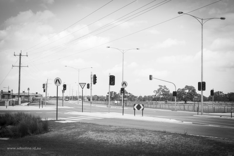 New intersection; poles, wires, traffic lights, signs.