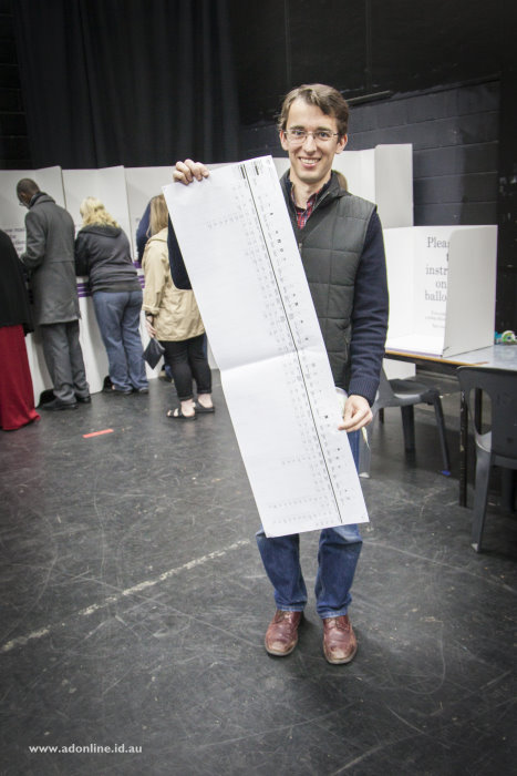 Adam Dimech standing with the Senate ballot paper for Victoria showing its length.