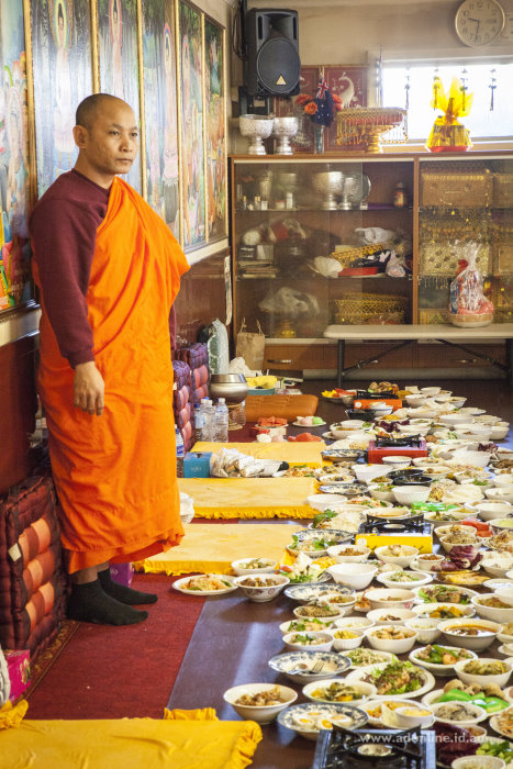 A Buddhist monk overlooking the festivities with the food offerings at his feet.
