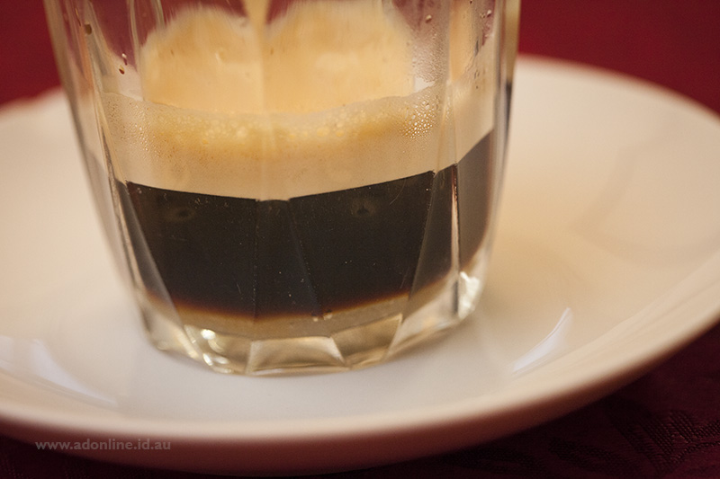 Close-up of glass with coffee crema visible.