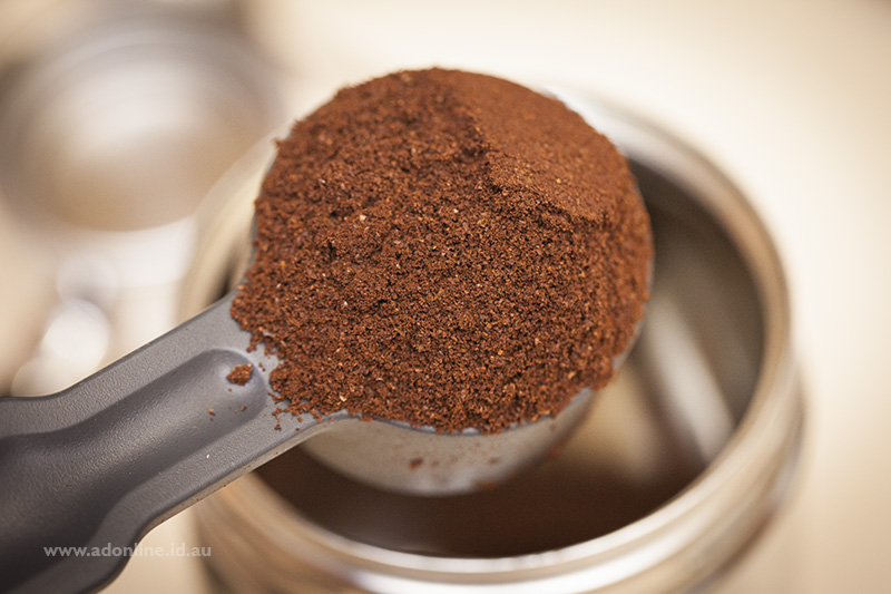 Close-up image of spoon heaped with coffee powder.