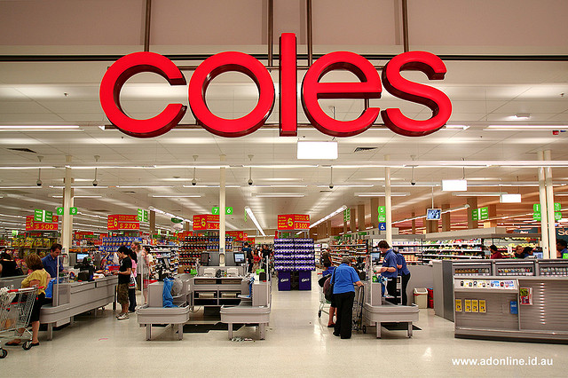 View into supermarket with row of registers and big 'Coles' sign hanging down.