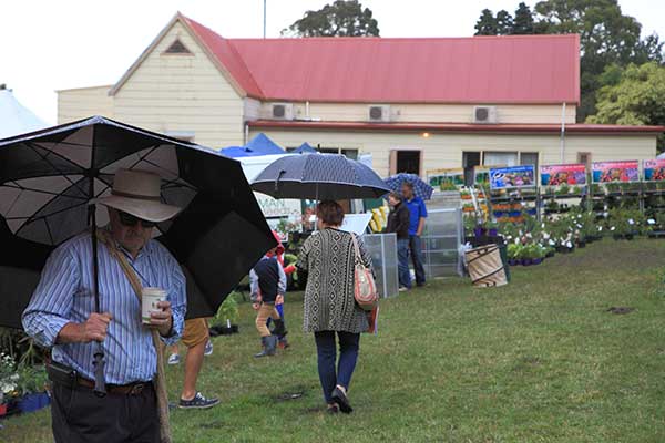 Man standing under umbrella at garden show.