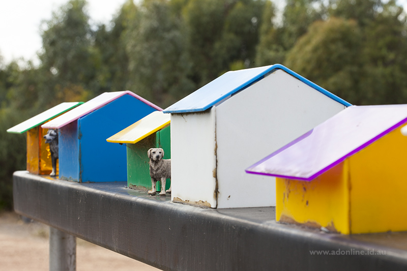 Sculpture of a row of kennels with dog beside.