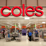 View into supermarket with row of registers and big 'Coles' sign hanging down.